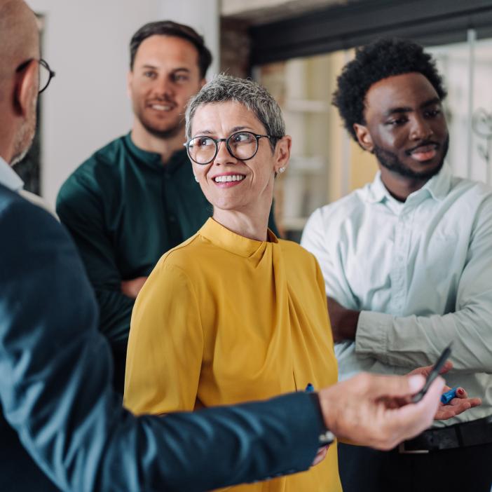 Four people stand near a whiteboard