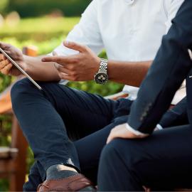 people on bench looking at iPad