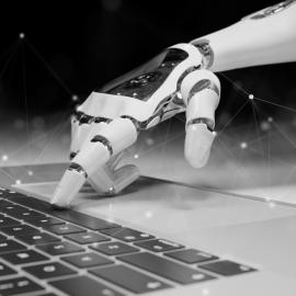 A robot hand typing on computer keyboard