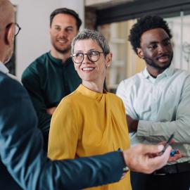 Four people stand near a whiteboard